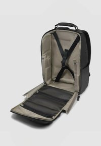 Sac à dos noir avec intérieur beige, doté de compartiments rembourrés, de bretelles réglables et de poches en mesh zippées pour une organisation optimale.