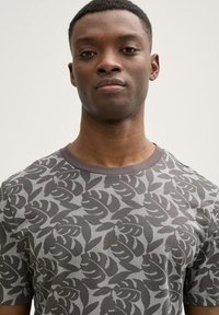 Szary t-shirt z krótkim rękawem z wzorem liści z naprzemiennymi paskami. Został zaprojektowany z okrągłym dekoltem i strukturalną tkaniną.