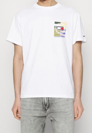 Weißes Baumwoll-T-Shirt mit einem mehrfarbigen grafischen Taschen-Design. Die Tasche umfasst Streifen, Blätter und Branding-Text am unteren Rand.