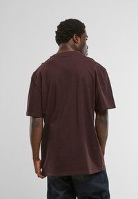 Burgunderfarbener Oversized-T-Shirt aus Baumwolle, mit Rundhalsausschnitt und kurzen Ärmeln, glatter Textur und ohne sichtbare Logos oder Muster.
