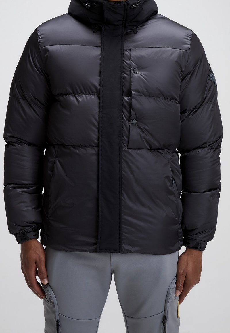 Veste matelassée noire avec boutons sur le devant et fermeture éclair, dotée d'un col montant et d'une capuche réglable, tissu texturé, et poches latérales.