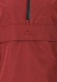 Röd tröja med halv dragkedja och broderad bergslogotyp. Har en texturerad tygkvalitet och en horisontell yoke över bröstet.
