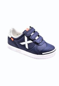 Zapatilla azul marino con material blanco perforado, correas de Velcro ajustables, suela blanca y un distintivo diseño blanco en forma de 'X' en el costado.