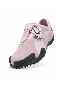 Baskets slip-on rose clair texturées avec semelle noire cloutée et un petit pendentif en forme de lapin fixé près de la bride.
