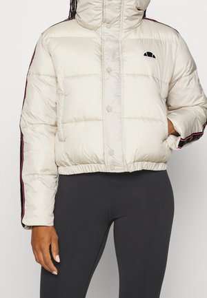 Biała krótka kurtka puchowa z zatrzaskami, czarno-różowe boczne paski, małe czarne logo na piersi, noszona z czarnymi legginsami.