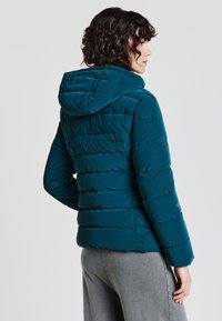 Türkiser Puffer-Jacke mit Kapuze, ausgestattet mit horizontalen Steppnähten, langen Ärmeln und einer glatten, glänzenden Oberfläche.