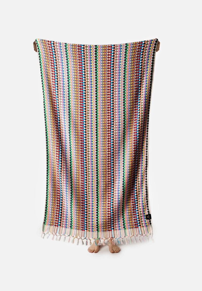 Multi-colored woven blanket with stripes in red, green, yellow, and blue. Features tassels along the edge and a textured surface.