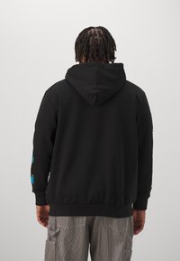 Černá mikina s kapucí a klokánkem, žebrovanými manžetami a lemem, s barevnými grafickými motivy na rukávech.