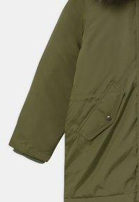 Oliwkowa, długa kurtka z długim rękawem, z gładką fakturą, z przednią kieszenią na zatrzask oraz ściągaczami przy rękawach.