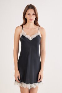 Vestito sottoveste in raso nero con spalline regolabili, caratterizzato da un delicato bordo di pizzo bianco intorno allo scollo e all'orlo. Tessuto liscio, lunghezza al ginocchio.