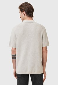 Korte mouwen gebreide polo in lichtbeige, met een gestructureerde stof, klassieke kraag en raglanmouwontwerp. Minimalistische stijl.