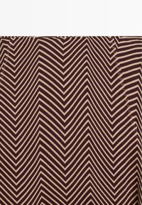 Tissu à motif chevron avec des rayures diagonales alternées brun foncé et beige formant des formes en V nettes.