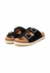 Sandali in suede nero con due fibbie in argento, soletta beige imbottita e suola in gomma bianca testurizzata. Design con punta aperta per una maggiore traspirabilità.