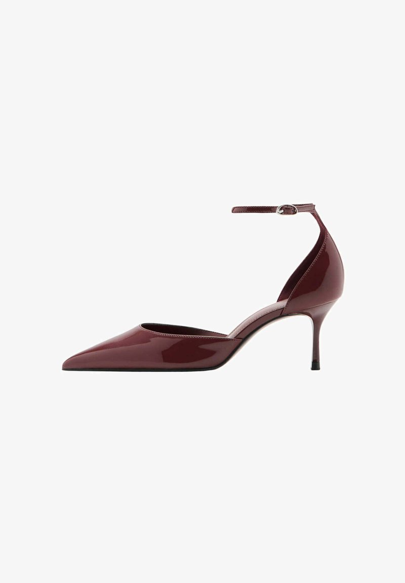 Chaussure à talon kitten brillante bordeaux à bout pointu avec bride à la cheville et boucle argentée sur fond blanc.