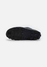 Schwarze Sportschuhsohle aus strukturiertem Gummi für Traktion, mit tiefen Rillen und einem verstärkten Zehenbereich für Haltbarkeit.