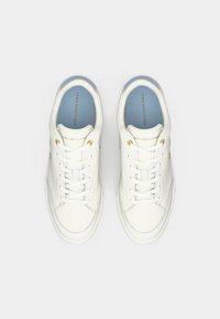 Hvite lær sneakers med lav profil, flate snørebånd, gull detaljer, og et lyseblått interiør med merkevarenavnet.