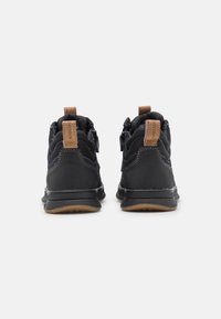 Czarne buty sportowe z teksturowaną cholewką, gumową podeszwą i brązowymi skórzanymi detalami. Posiadają wyściełany kołnierz oraz zamek błyskawiczny po bokach.