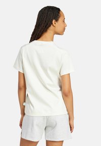 Weißes kurzärmliges T-Shirt aus Baumwollmischung, mit einer leichten Textur, Rundhalsausschnitt und dezentem Markenlogo auf der Rückseite.