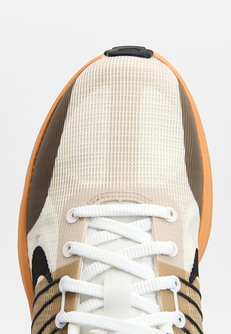 Sneaker con una toma in crema testurizzata, accenti marroni e una suola in gomma arancione. Presenta lacci bianchi e una linguetta nera.