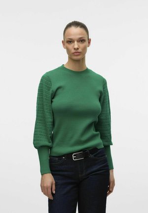 Green knit sweater with textured puff sleeves, round neckline, and ribbed cuffs, paired with dark jeans and a black belt.