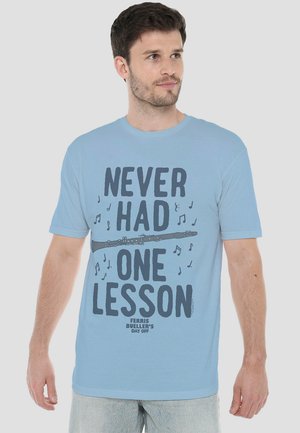 Light blue cotton t-shirt featuring bold black text "NEVER HAD ONE LESSON," a flute illustration, and musical notes. Casual fit, short sleeves.