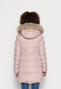 Hellrosa gepolsterte Jacke mit einer mit Fell besetzten Kapuze, vertikaler Steppung und langen Ärmeln, die eine figurbetonte Silhouette und eine Länge bis zur Mitte des Oberschenkels aufweist.