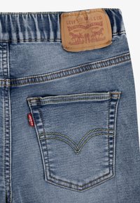 Los jeans de mezclilla azul de Levi's cuentan con un parche de cuero, costuras en contraste y un diseño distintivo en el bolsillo trasero con una etiqueta roja.