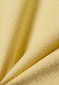Gelber Stoff mit einer weichen, strukturierten Oberfläche und einem gerippten Muster. Das Material wirkt leicht und flexibel.