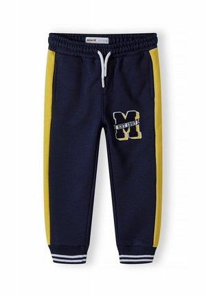 Pantalones jogger azul marino con franjas laterales amarillas, cintura elástica con cordón blanco, puños rayados en los tobillos y parche con "M EST 1997" en el muslo izquierdo.