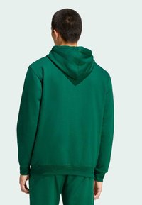 Zelená mikina s kapucňou vyrobená z jemného materiálu, s voľným strihom, rebrovanými manžetami a pásom. Bez viditeľných vzorov alebo hardvérových detailov.