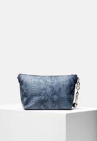 Niebieska torebka kopertówka w wzór wężowej skóry z zamkiem błyskawicznym i złotym łańcuszkiem, umieszczona na białym postumencie na tle o jednolitym kolorze.