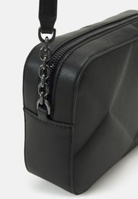 Borsa a tracolla nera in pelle con forma rettangolare, superficie texture, chiusura con zip superiore e tracolla con dettagli in catena.