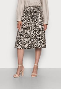 Beige rok tot op de knie met zwarte zebrastripes, voorzien van een elastische tailleband. Gecombineerd met beige, gestripte hoge hakken.