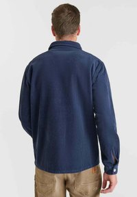Camicia button-up in corduroy blu navy con colletto a giogo, maniche lunghe e dettaglio a fessura nei polsini. Tessuto a coste testurizzato.