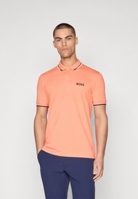 Polo arancione con colletto classico, chiusura a due bottoni e dettagli neri e bianchi sul colletto e sulle maniche. Logo "BOSS" sul petto.