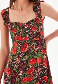 Blumenkleid mit schwarzem Hintergrund, lebhaftem orangefarbenen Obst- und grünen Blattmustern, quadratischem Ausschnitt und Rüschenträgern.