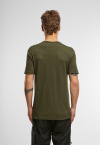 Olive zaļas krāsas T-krekls, izgatavots no mīksta auduma, ar apaļu dekoltē un īsām piedurknēm, ar vienkāršu dizainu un pieguļošu griezumu.
