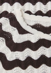 Tissu tricoté avec des rayures en dents de scie alternées marron foncé et blanc, présentant des motifs ajourés et des vagues texturées.