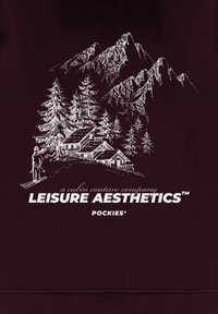 Felpa color bordeaux con design illustrato bianco di montagne, alberi e una baita, con testo "Leisure Aesthetics" e dettagli ispirati all'equipaggiamento per la neve.