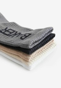 Rippensocken in Grau, Schwarz, Beige und Weiß, gestapelt mit einem Logo auf dem grauen Paar. Hergestellt aus Strickmaterial, mit unterschiedlichen Texturen.