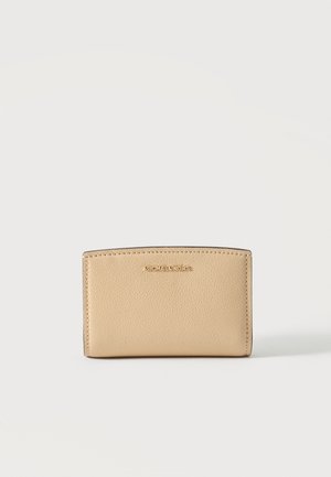 Bézs, texturált bőr Michael Kors pénztárca arany logóval, középen elöl, egyszerű háttér előtt.