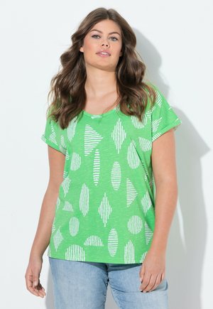 Grünes T-Shirt mit kurzen Ärmeln, das weiße geometrische Muster wie Streifen und ovale Formen zeigt, aus einem weichen, leichten Stoff gefertigt.
