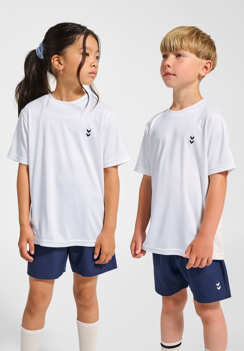 Vita kortärmade sporttröjor med svart chevronlogotyp på bröstet, i kombination med marinblå shorts och knähöga vita strumpor.