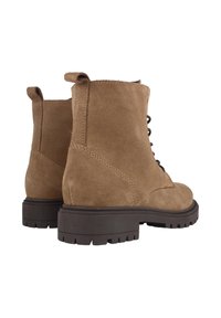 Botas de tobillo de ante marrón con suela rugosa y parte delantera con cordones. Presenta detalles cosidos y una pestaña de agarre para facilitar su puesta.
