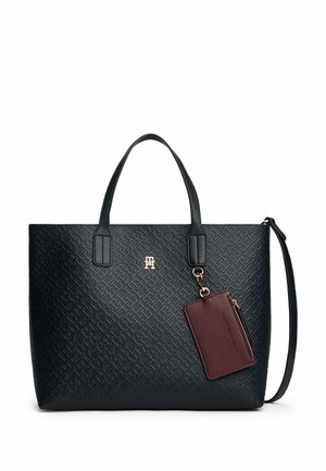 Sac fourre-tout noir texturé avec poignées doubles, logo doré et porte-carte bordeaux détachable relié par une chaîne dorée.