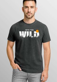 Schwarzes Baumwoll-T-Shirt mit dem Text "INTO THE WILD" und einer Grafik eines Sonnenuntergangs sowie Waldsilhouetten. Kurze Ärmel und runder Halsausschnitt.