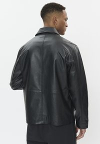 Black leather jacket with a smooth texture, featuring a folded collar, long sleeves, and a classic cut, viewed from the back.