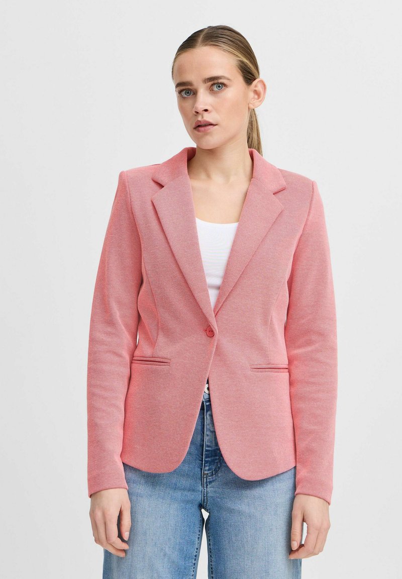 Rosa blazer med ett texturerat tyg, enkel knappstängning, insvängt krage och två framfickor, i kombination med ljusblå jeans.