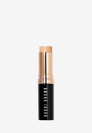 Stiftfondation in einer schwarzen Tube mit goldenen Akzenten. Verfügt über eine cremige, hellbraune Spitze und den Markennamen "BOBBI BROWN" in weißem Text.