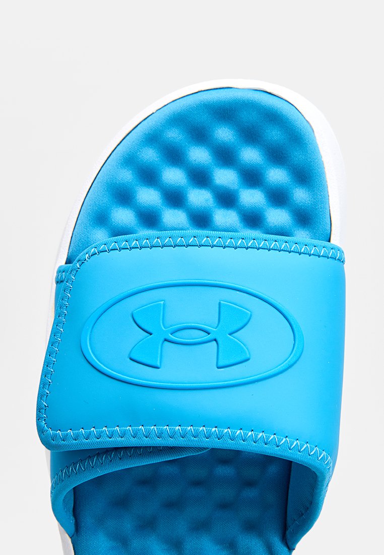 Blaue Rutschsandale mit einer strukturierten Schaumfußbett und einem glatten Gummiriemen mit erhabenem Logo. Die weiße Außensohle kontrastiert mit dem Design.